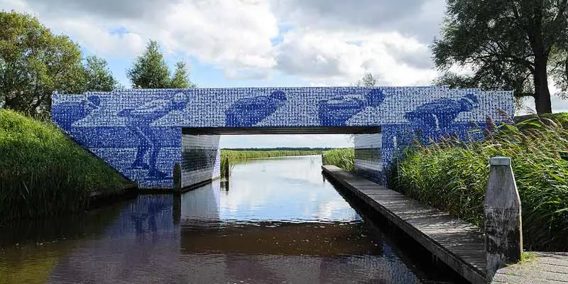 Blue and white tiled bridge over a flat canal in Friesland, the Netherlands