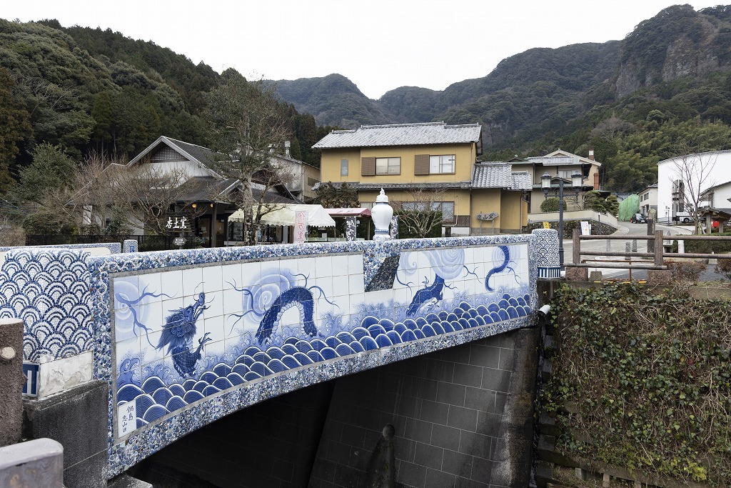 Blue and white porcelain bridge at Okawachiyama, framed by mountains and kiln houses