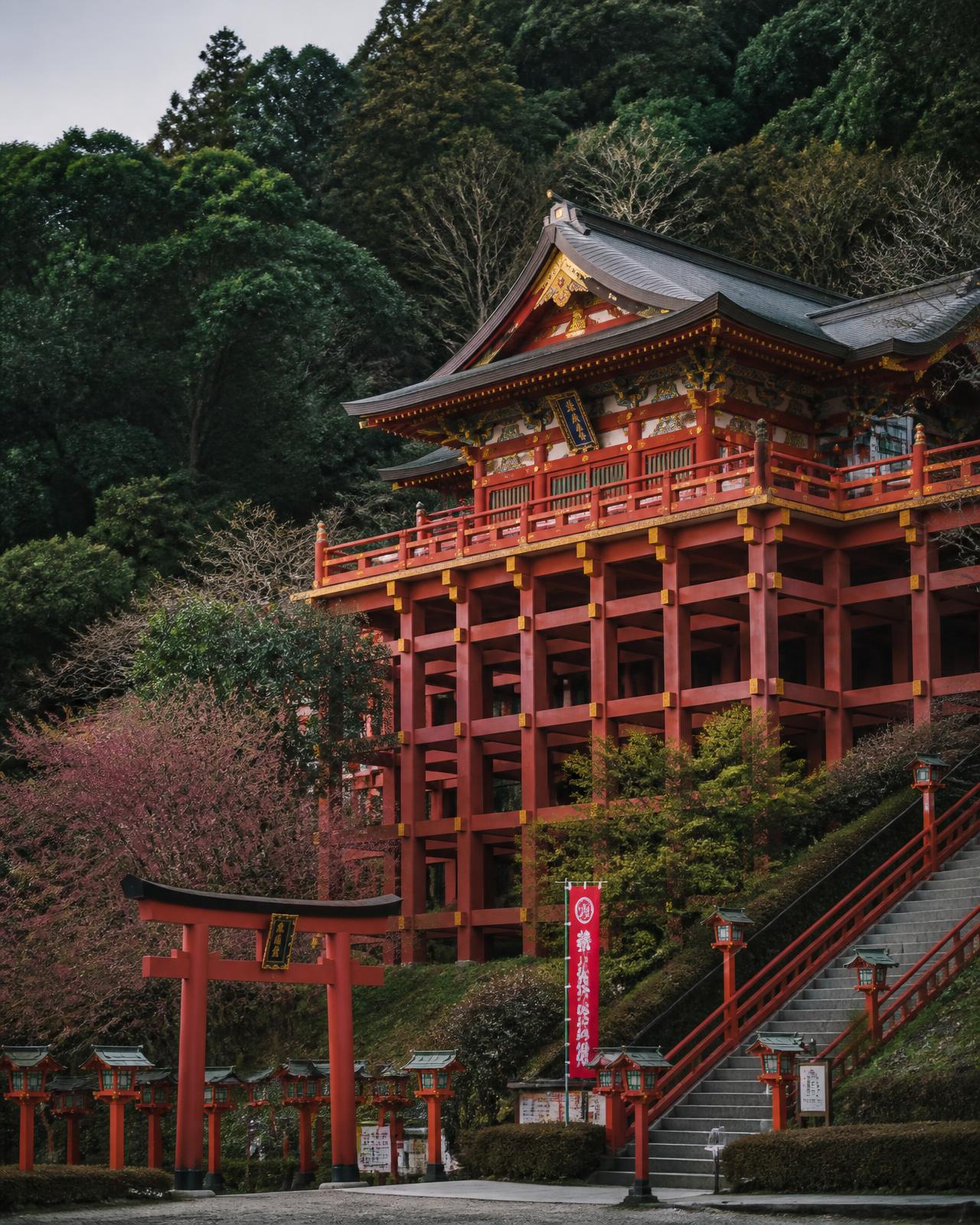 Vermilion Yutoku Inari shrine raised on wooden stilts against a forested hillside