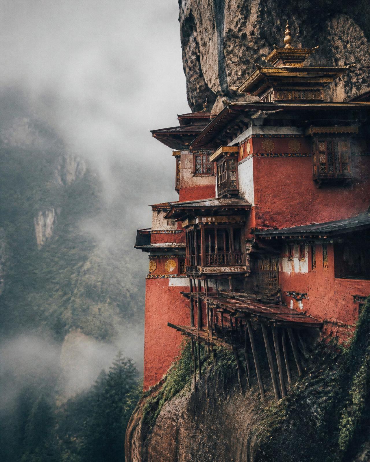 Red cliffside monastery in Bhutan surrounded by mist